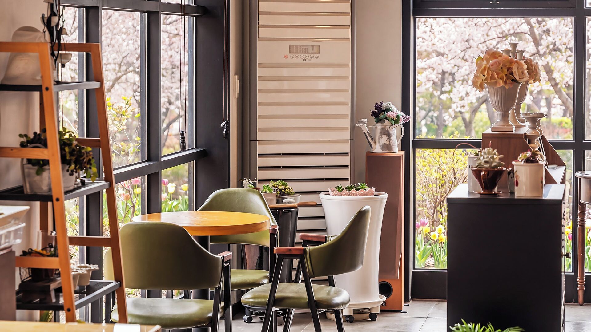 Un interior moderno con comedor, un ventanal con vistas a árboles y una estantería.