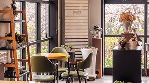 Un interior moderno con comedor, un ventanal con vistas a árboles y una estantería.