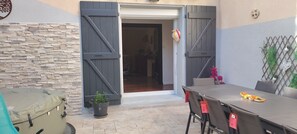 Eine Terrasse im Freien mit Tisch und Stühlen, einem überdachten Gegenstand und einem Blumentopf.