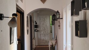Un pasillo con un letrero que dice 'VENUE', suelo de madera, una decoración con forma de corazón en la pared y una silla a lo lejos.