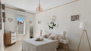 Un dormitorio con cama, mesitas de noche, lámpara y ventana.