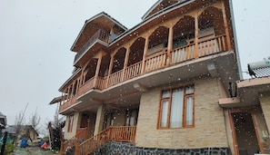 Un edificio de varios pisos con balcones, fachada de piedra y una chimenea.