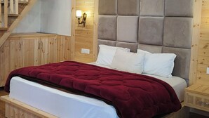 A wooden-paneled bedroom with a bed, a nightstand, a wall-mounted lamp, and a wooden staircase. - Not just a stay, a peaceful escape into nature.” (Bali Chowki)