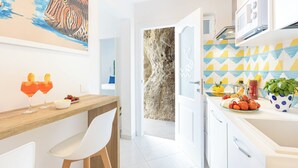 Una cocina moderna con encimera de madera, sillas blancas y zona de comedor.