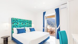 Habitación de hotel con una cama grande, una silla, una mesita y vistas a las montañas desde la ventana.