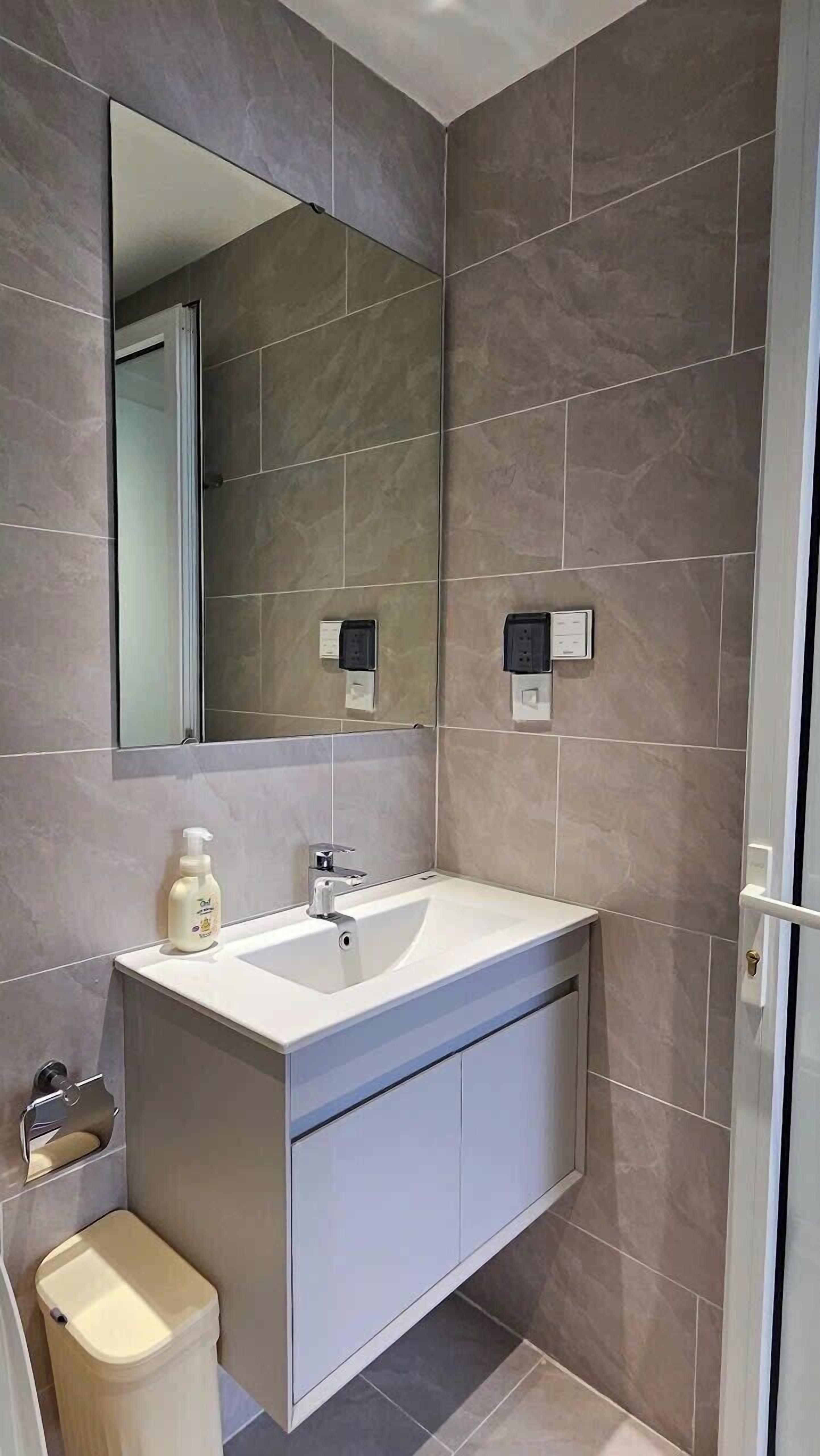 A modern bathroom with a white sink, mirror, and toilet.