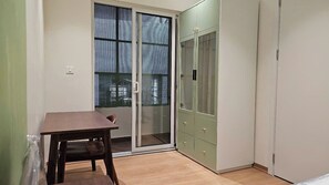 A room with a sliding glass door, a wooden table, and a green cabinet. - Joy Apartment Pearl West Lake (Tay Ho)