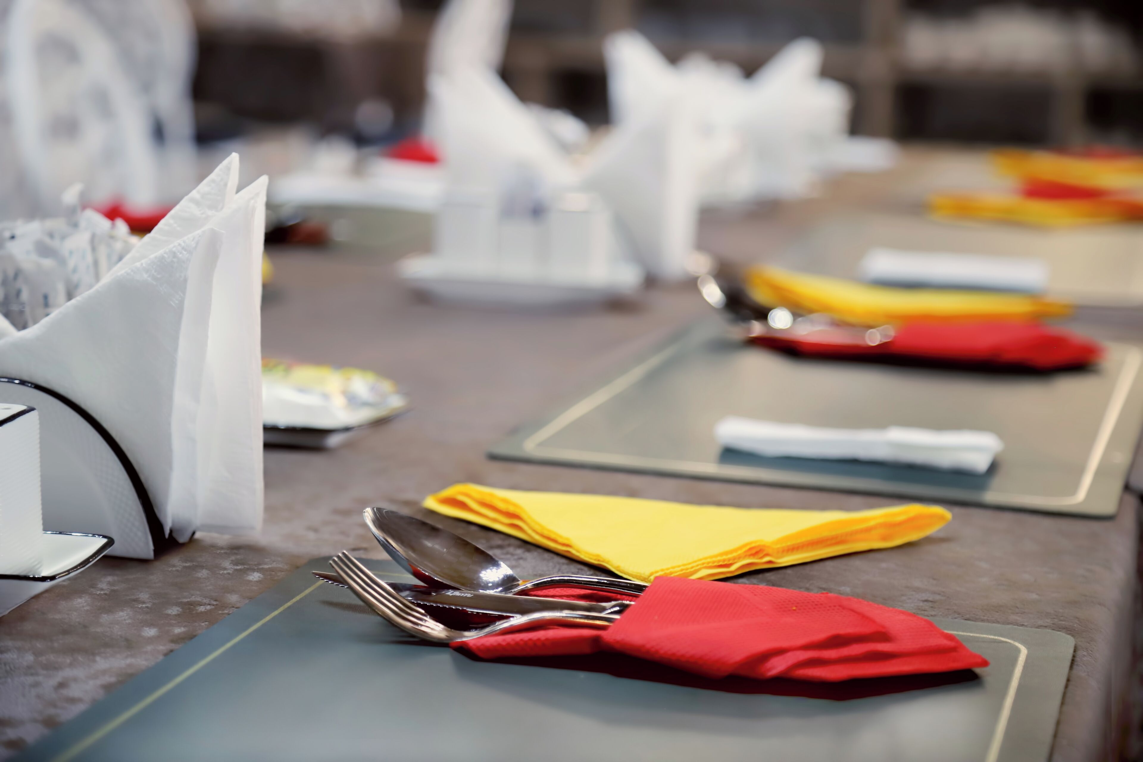 Mesa dispuesta con cubiertos y servilletas, lo que sugiere un restaurante.