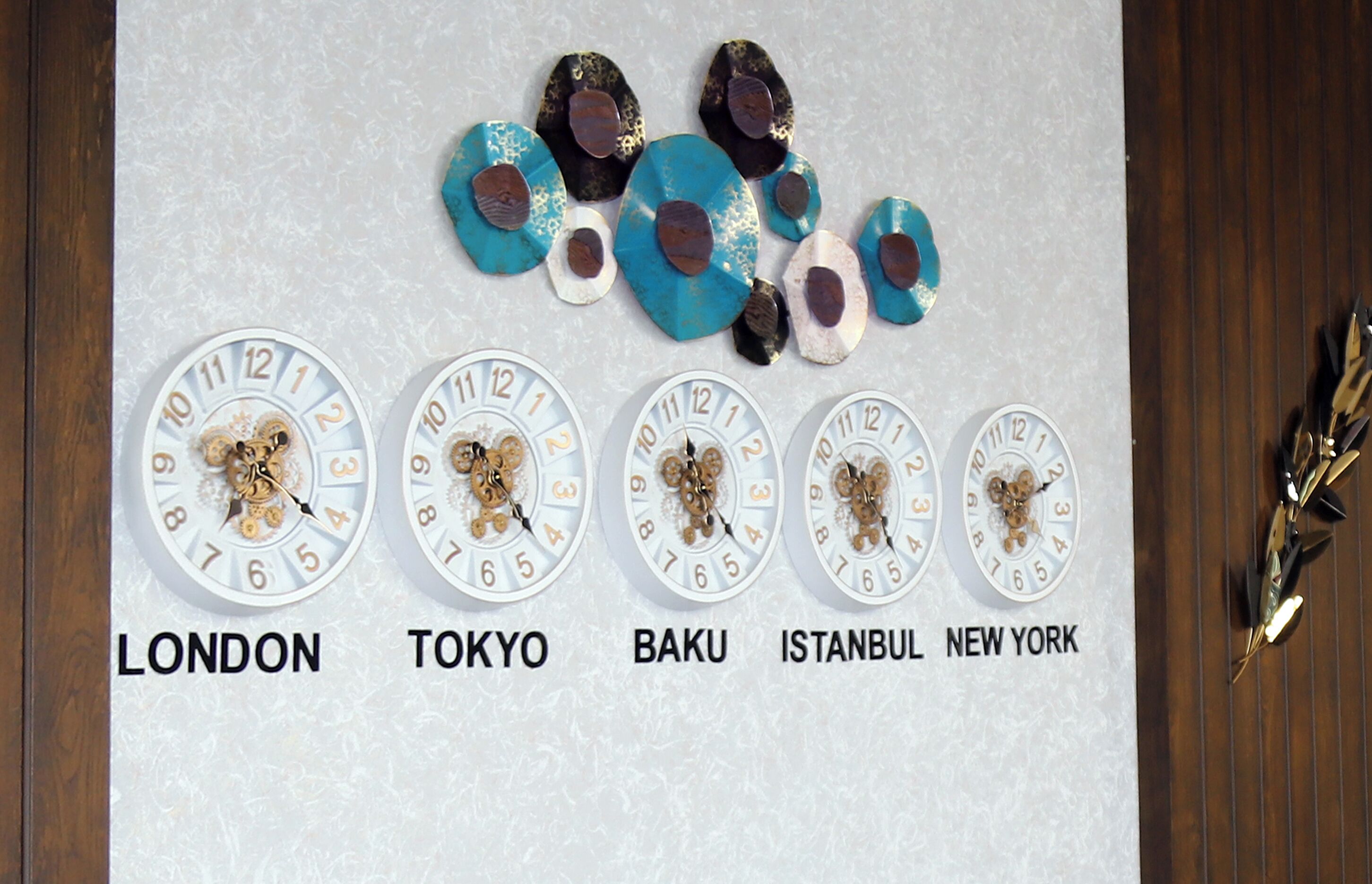 Una pared con relojes que indican nombres de ciudades.