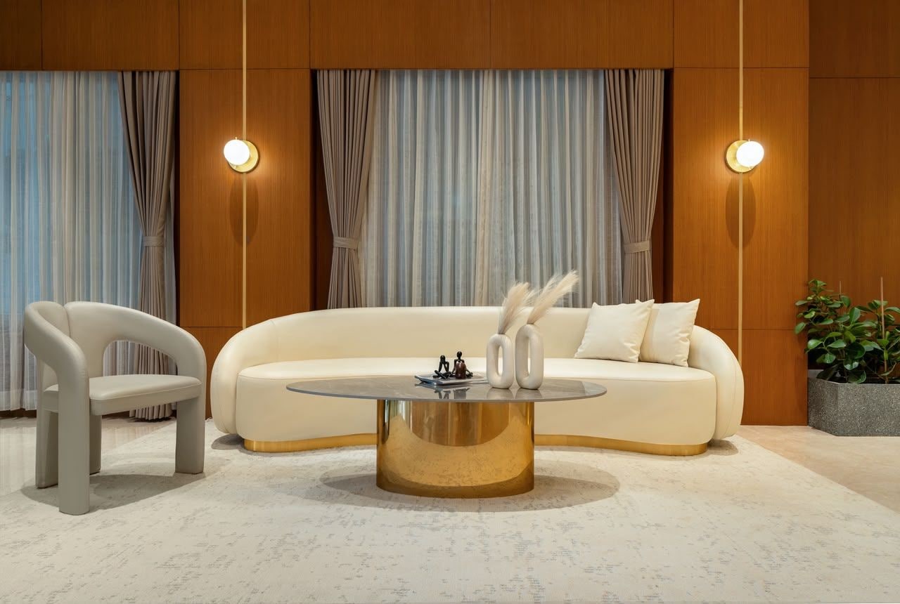 Una sala de estar moderna con un sofá, dos sillones, una mesa de centro y una planta en maceta.