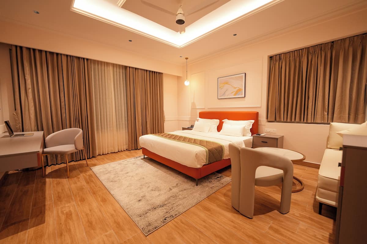 Ein modernes Hotelzimmer mit Bett, Schreibtisch, Stuhl und einem großen Fenster mit Vorhängen.