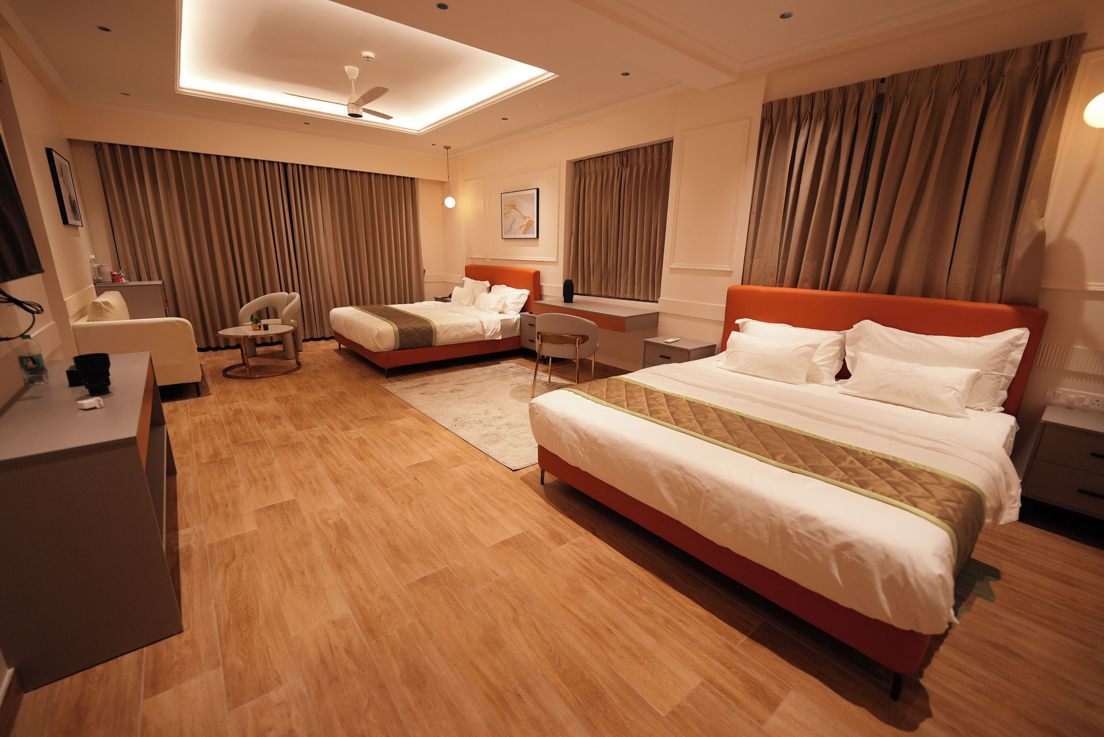 A hotel room with a large bed, a smaller bed, a desk, a chair, and a ceiling light.