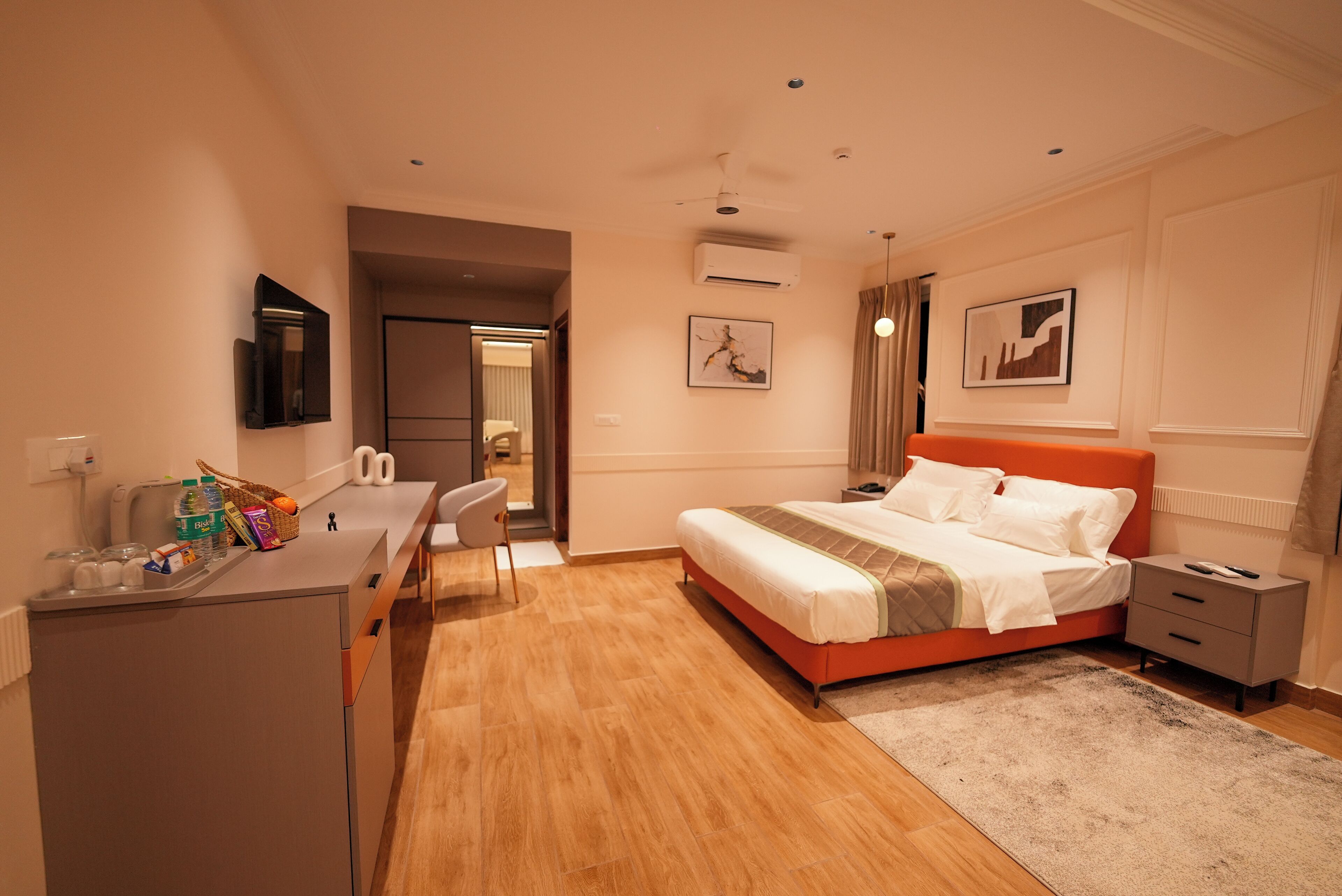 Ein Hotelzimmer mit Bett, Schreibtisch, Stuhl, Nachttisch und einem an der Wand befestigten Fernseher.