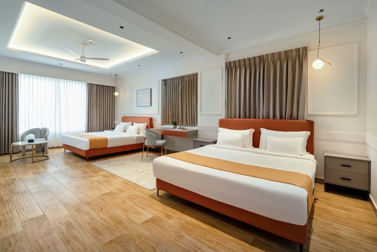 Habitación de hotel con dos camas, un escritorio, una silla y un ventilador de techo.