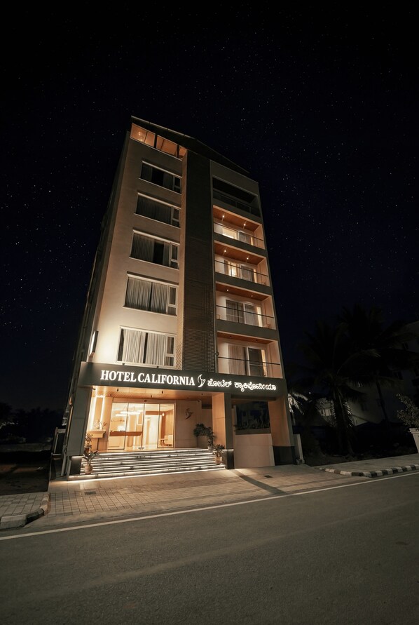 Un hôtel à plusieurs étages, doté d’une enseigne lumineuse, d’une entrée bien éclairée et offrant une vue dégagée sur le ciel.