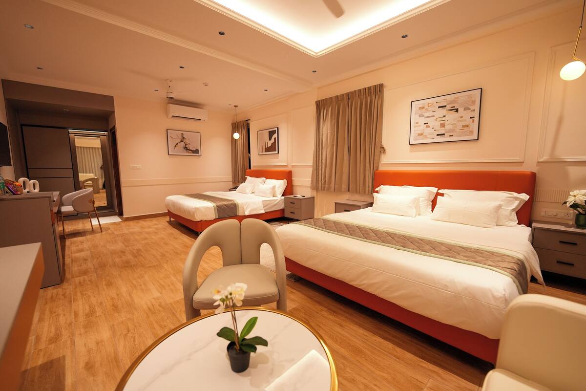 Ein Hotelzimmer mit einem Bett, zwei Nachttischen, einem Schreibtisch, einem Sessel und einem kleinen Tisch mit einer Pflanze.