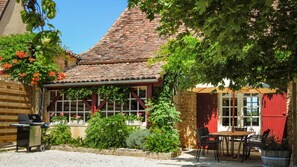 A rustic building with a tiled roof, a covered patio area, and a dining table with chairs. - SADDLER (Sainte-Foy-de-Longas)