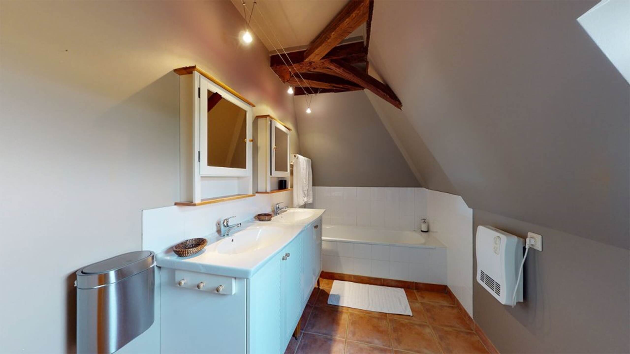 A modern bathroom with a large mirror, a bathtub, and a toilet.