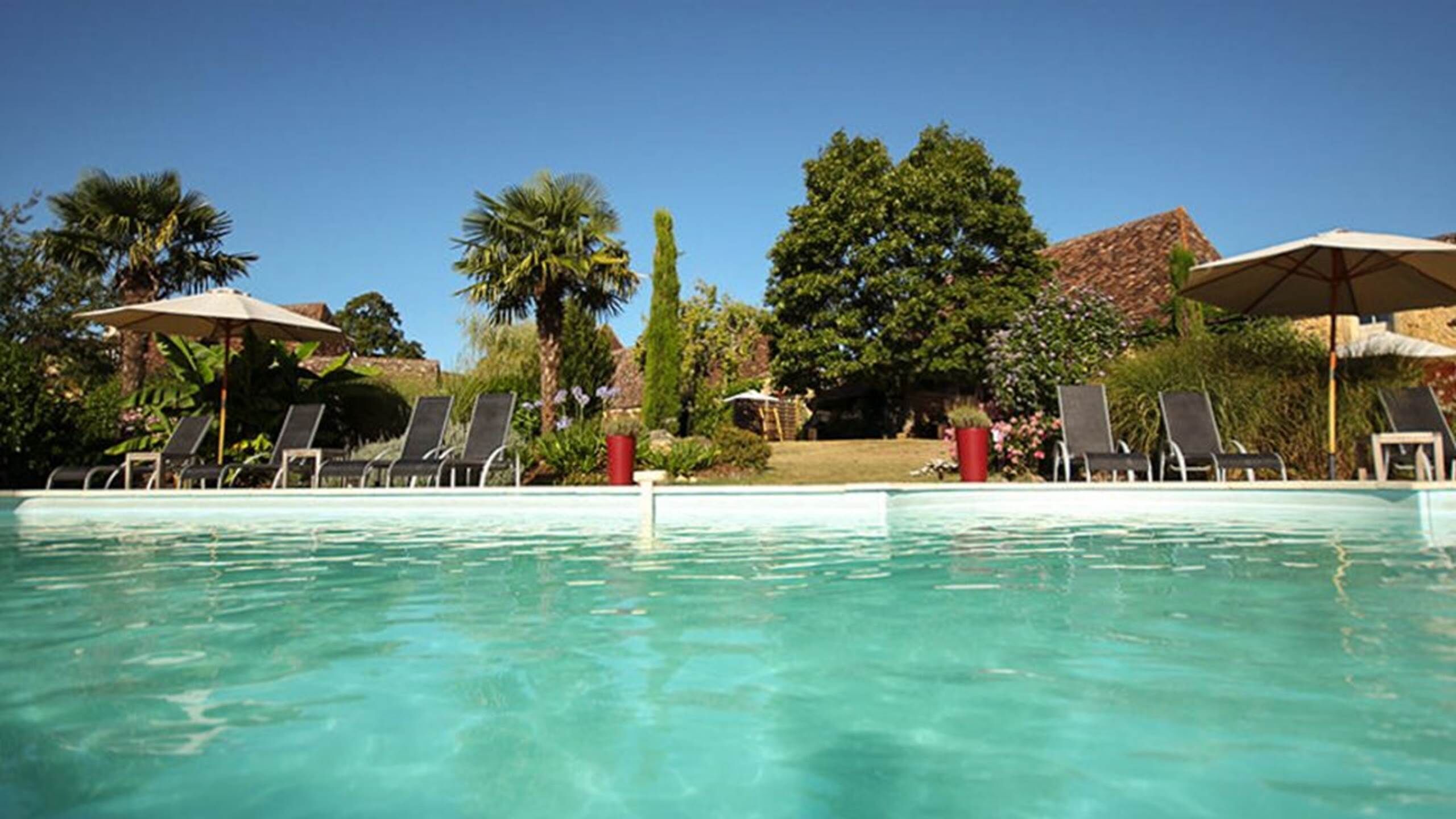 Ein Schwimmbecken mit Liegestühlen und Sonnenschirmen.