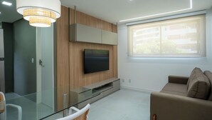 A modern living room with a flat-screen TV, glass dining table, and a sofa. - Flat Praça do Parnamirim by Easy Home (Recife)