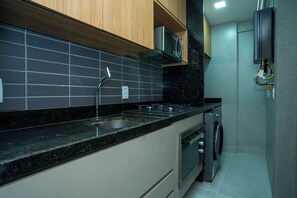 Una cocina moderna con un lavamanos de acero inoxidable, un microondas, una estufa y un horno empotrado.