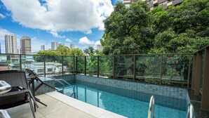 A rooftop pool with clear blue water, surrounded by glass railings and a view of city buildings. - Flat Praça do Parnamirim by Easy Home (Recife)