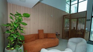 A modern interior with a sofa, a white armchair, and a potted plant. - Flat Praça do Parnamirim by Easy Home (Recife)