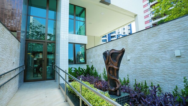 A modern building with a glass entrance, a metal railing, and a sculpture. - Flat Praça do Parnamirim by Easy Home (Recife)