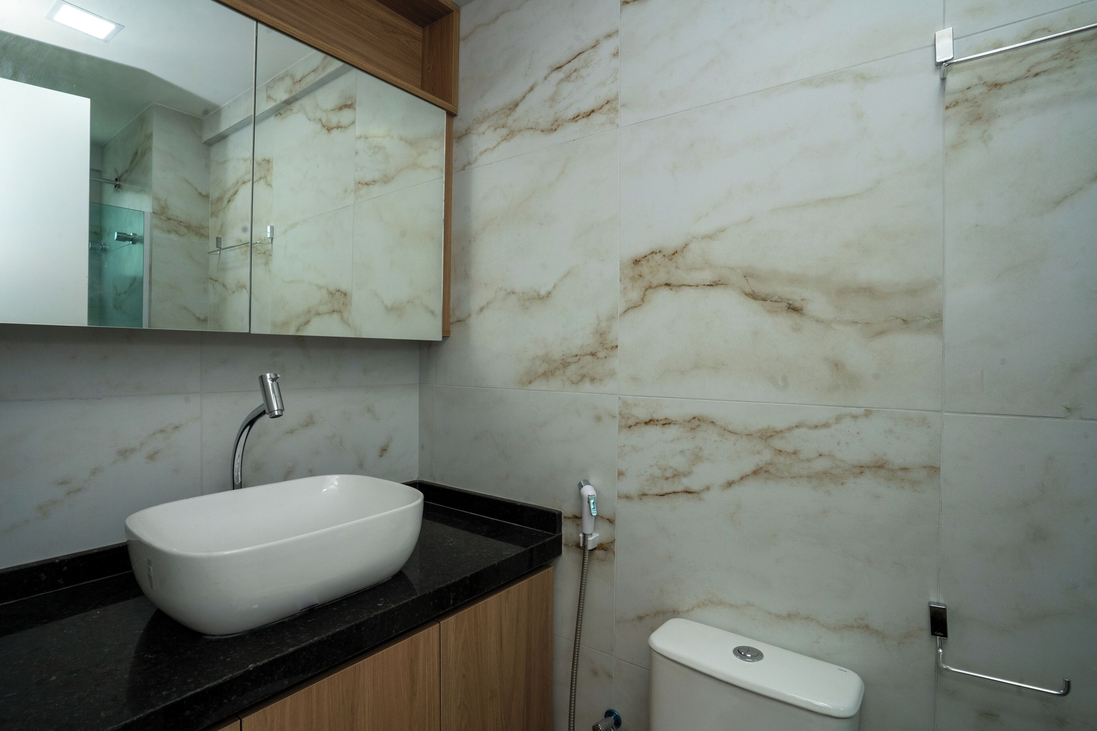 A bathroom with a white sink, a mirror, a shower, and a toilet.