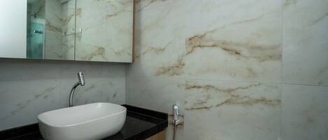 A bathroom with a white sink, a mirror, a shower, and a toilet.
