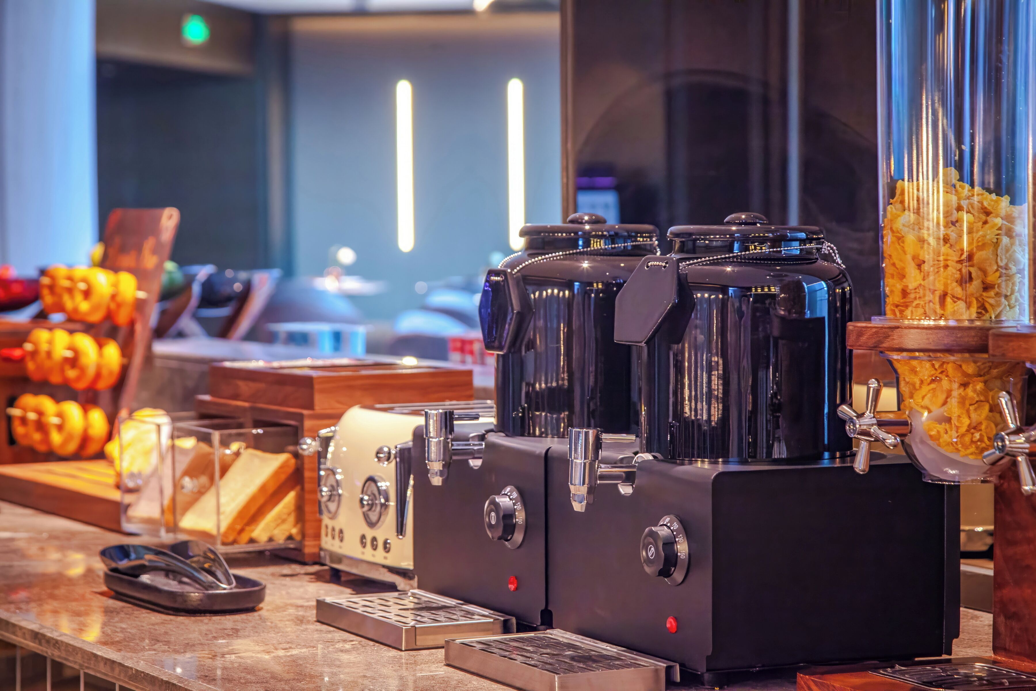 A coffee machine with multiple brewing options, a cash register, and a glass display case with pastries.