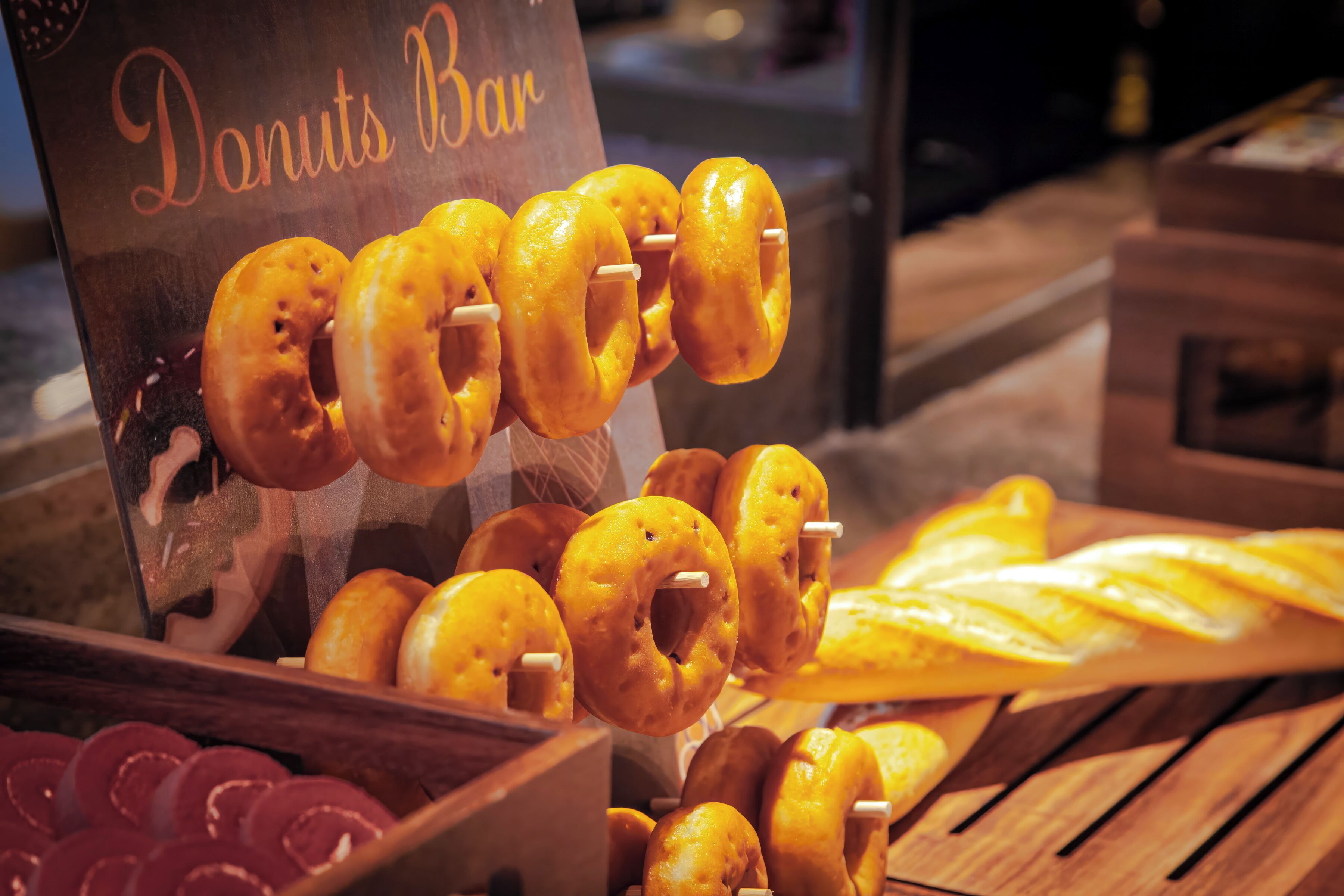 A display of donuts at a bakery counter with a sign reading 'Donuts Bar'.