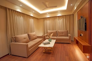 A modern living room with two sofas, a coffee table, and a ceiling fan.