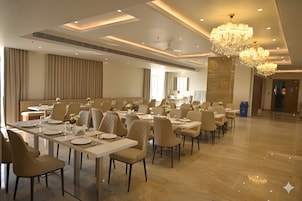 A spacious dining area with multiple tables and chairs, a chandelier, and a large mirror.