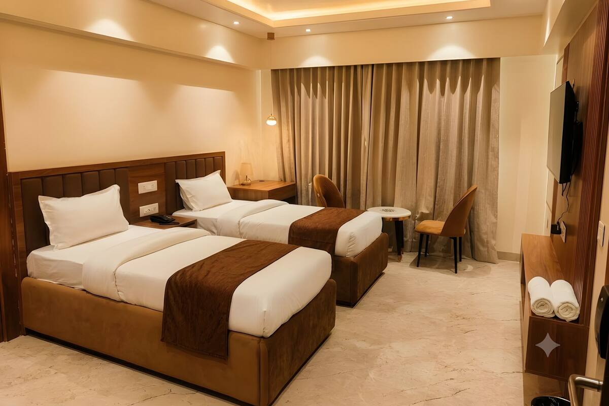 A hotel room with two beds, a desk, a chair, a television, and a ceiling fan.