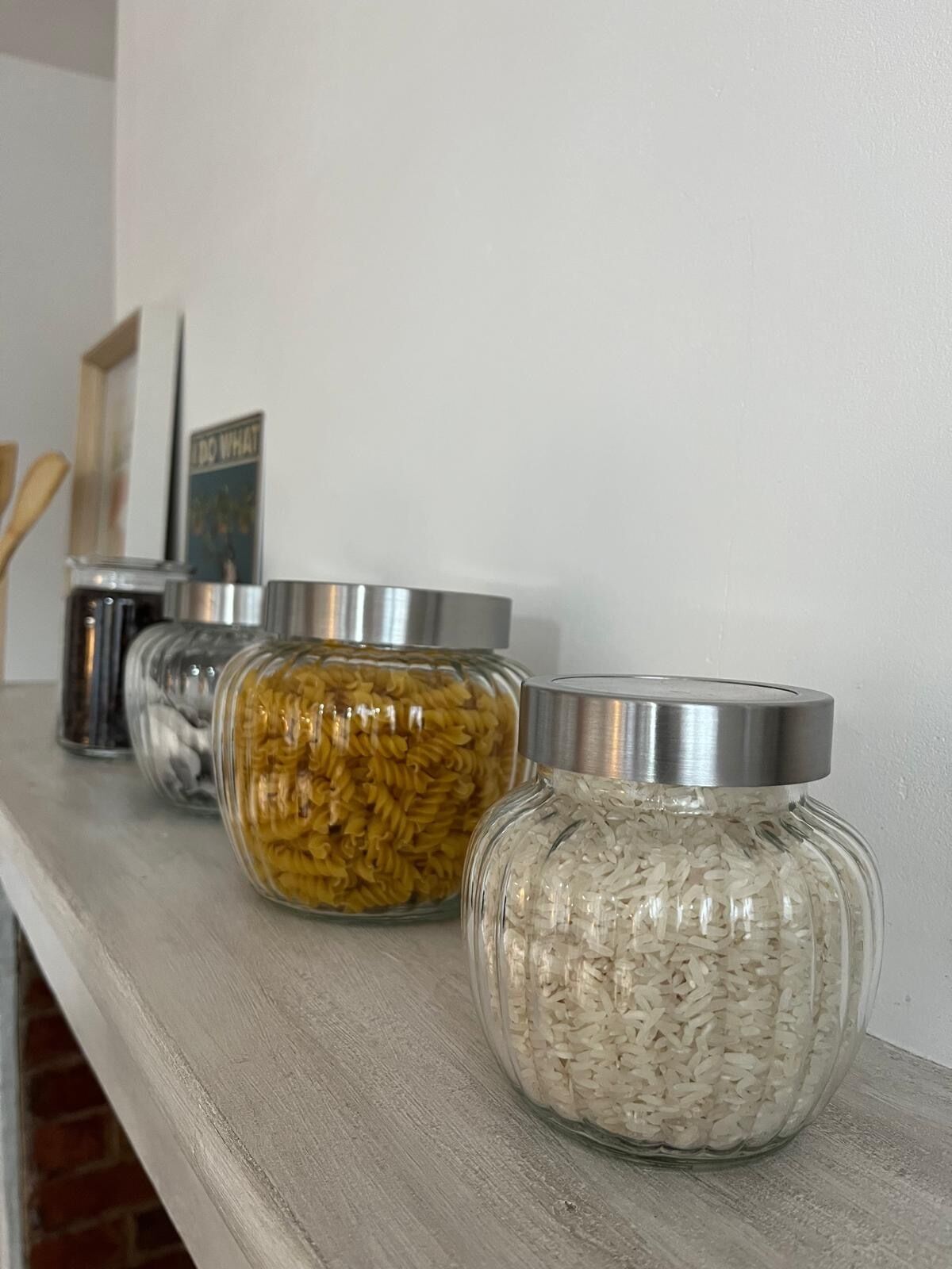 Three glass jars with metal lids on a wooden shelf.