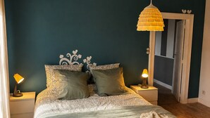 A bedroom with a bed, two bedside lamps, a hanging lamp, and a door leading to another room. - Cosy gite la maison bleue in vineyards and earth, near Epernay Reims (Chaltrait)