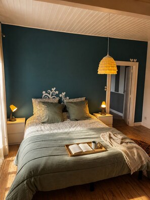 A bedroom with a bed, two bedside lamps, a hanging lamp, and a door leading to another room. - Cosy gite la maison bleue in vineyards and earth, near Epernay Reims (Chaltrait)