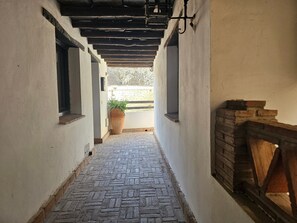 A narrow corridor with patterned paving, a potted plant, and a brick fireplace. - Apartment 'Your Ohanes Retreat' with Mountain Views, Balcony and Wi-Fi (Ohanes)