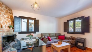 A living room with a fireplace, a glass dining table, a sofa, and a heater.