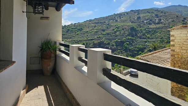 A balcony with a view of terraced fields and a mountain.