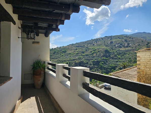 Un balcon avec vue sur des champs en terrasses et une montagne.