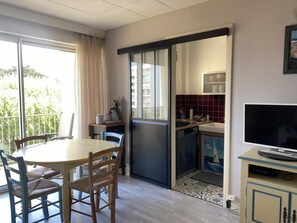 A modern kitchen with a coffee machine, a TV, and a dining area with a table and chairs. - Apartment close to Quiberon's long beach and Thalasso spa (Quiberon)