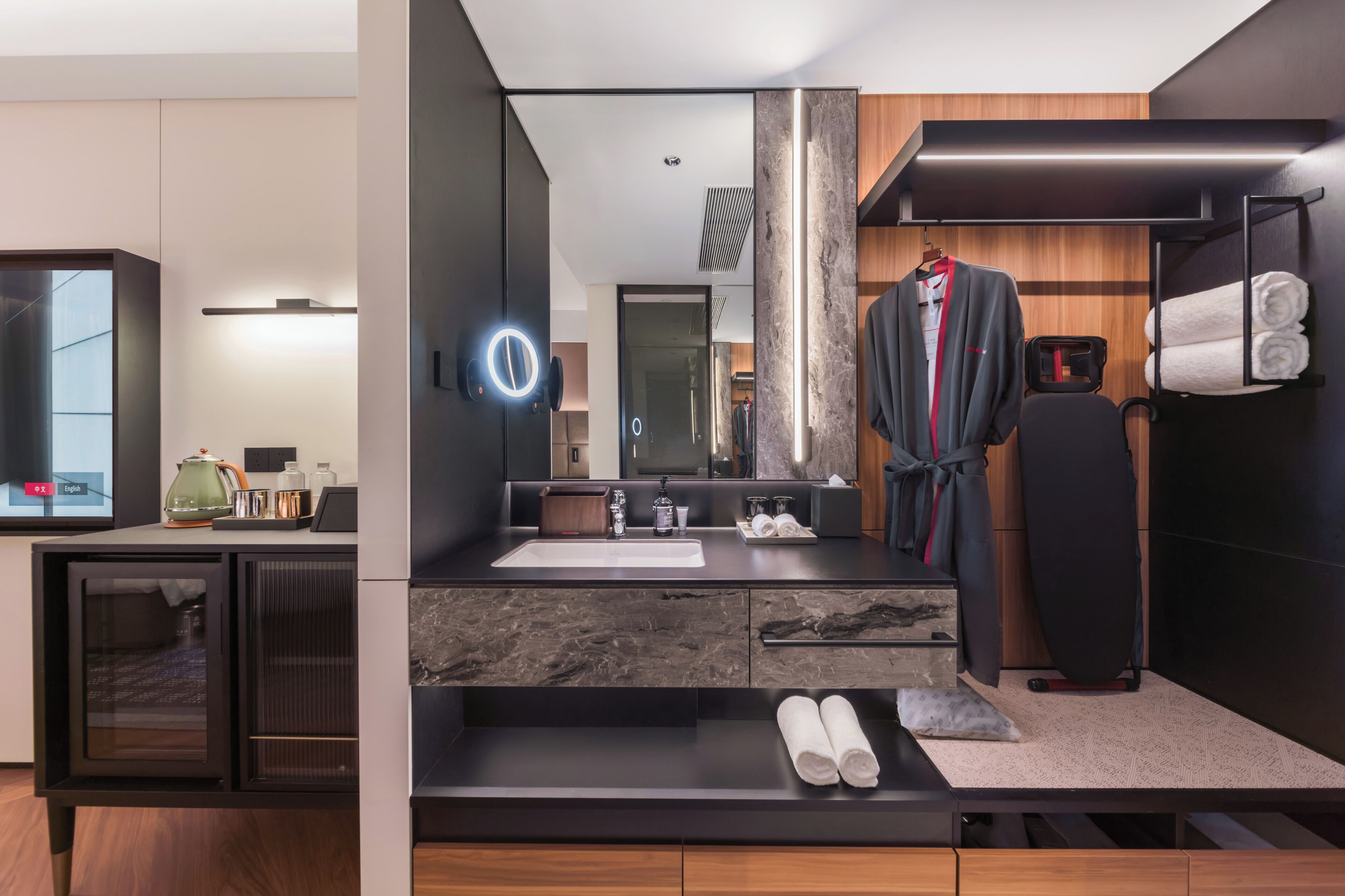 A modern bathroom with a large mirror, a sink, a robe rack, and a towel rack.