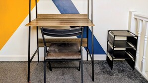A bunk bed with a wooden top shelf and a chair, against a wall with a geometric pattern. - Harold House (Leeds)