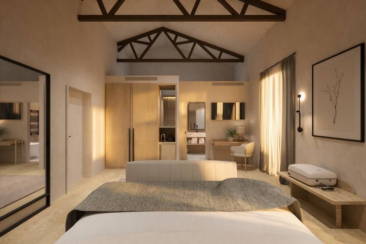 Una habitación de hotel moderna con cama, mesita de noche, armario y un baño visible a través de una puerta abierta.