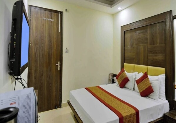 Una camera d'albergo con un letto, una televisione e una porta in legno.