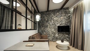 Un interior moderno con una pared de piedra, un televisor de pantalla plana, una mesa de centro redonda y un comedor con mesa y sillas.