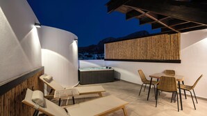 Una terraza en la azotea con sillones, una mesa y un jacuzzi.