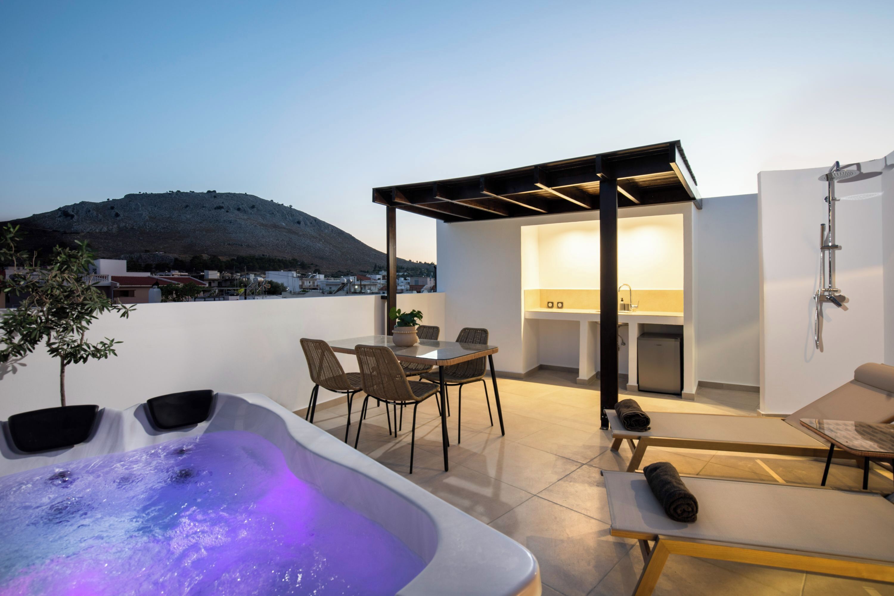 A rooftop terrace with a hot tub, seating area, and a kitchen.